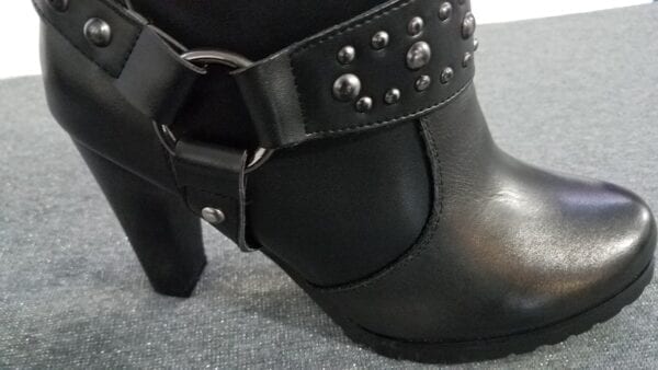 Closeup on black leather boot with heel and buckle